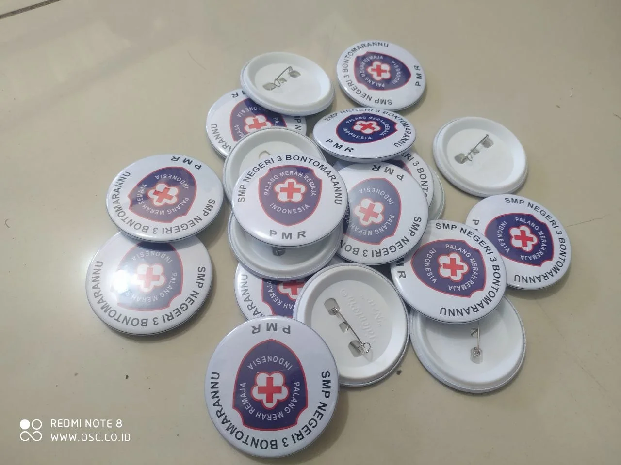 Contoh pin biasa 58 mm custom dengan logo PMR dan peniti di bagian belakang