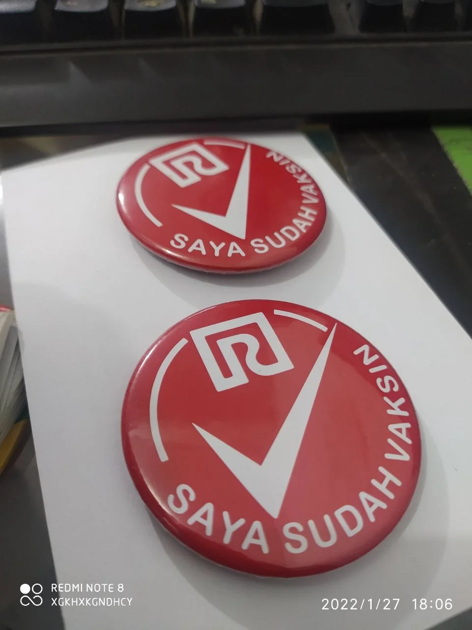 Contoh pin bulat custom dengan tulisan dan desain merah